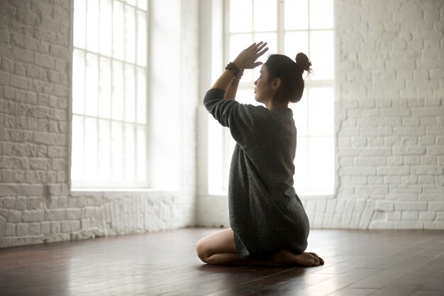 Jeune femme séduisante dans vajrasana pose, studio loft blanc