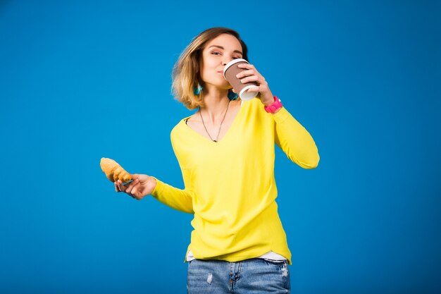 Jeune femme séduisante élégante en chemisier jaune sur bleu