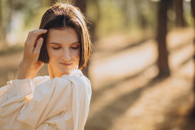 Jeune femme séduisante en robe blanche en forêt