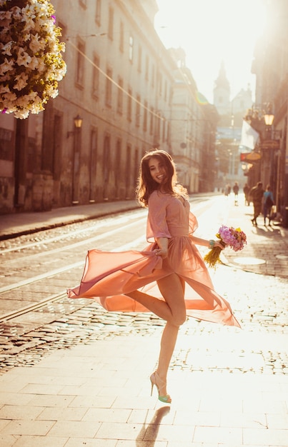 Une jeune femme séduisante en robe légère tourne dans la lumière du matin