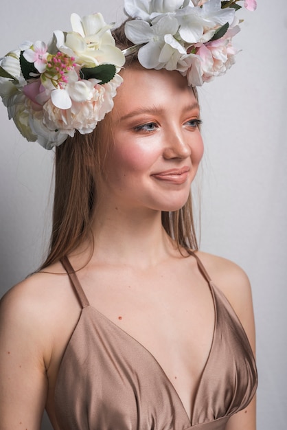 Photo gratuite jeune femme sensuelle souriante en robe avec une couronne de belle fleur