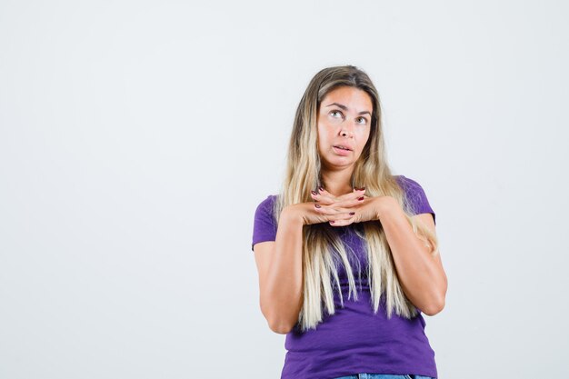 Jeune femme serrant les doigts en t-shirt violet et à la vue de face, pleine d'espoir.