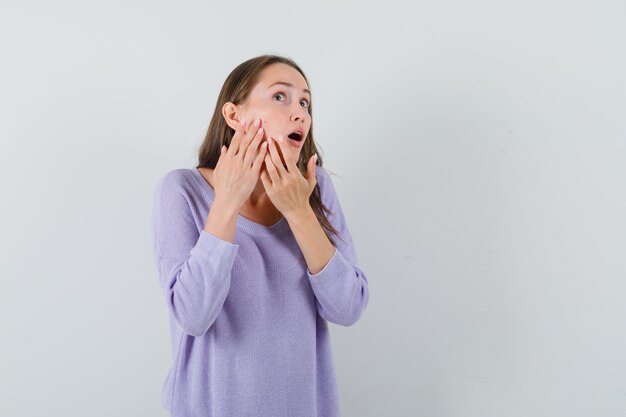 Jeune femme serrant son bouton sur la joue en vue de face de chemise décontractée.