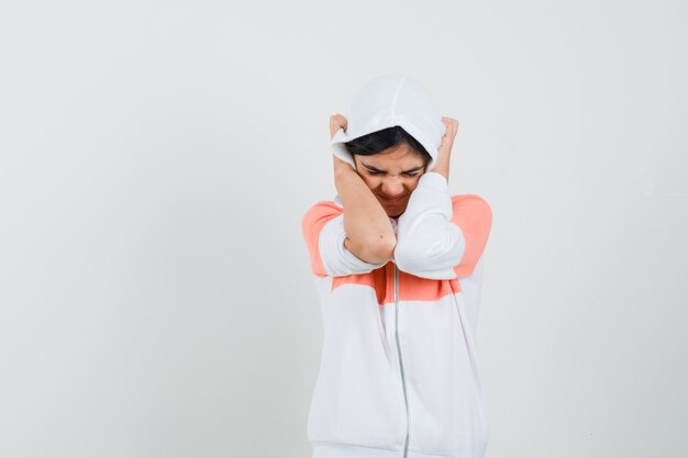 Jeune femme serrant la tête avec ses mains en sweat à capuche et à la recherche de stress.