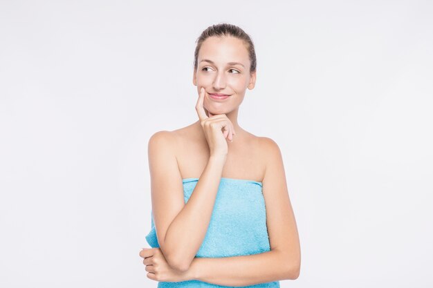 Jeune femme en serviette bleue sur fond blanc