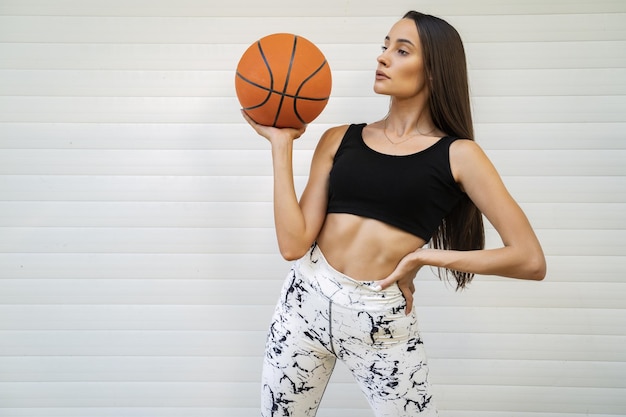 Photo gratuite jeune femme sexy portant un soutien-gorge de sport et des leggings et tenant un ballon de basket