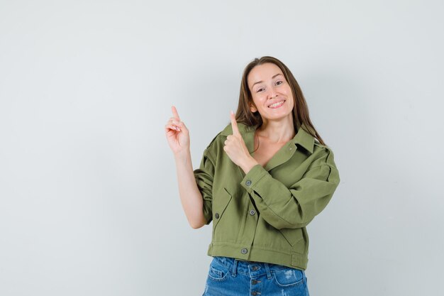 Jeune femme en short veste pointant vers le haut et à la recherche de plaisir