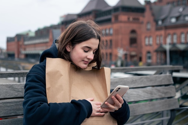 Une jeune femme avec un smartphone et un colis dans les mains