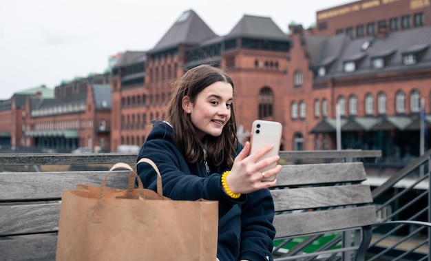 Une jeune femme avec un smartphone et un colis dans les mains