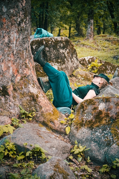 Jeune femme solitaire dormant près d'un arbre et à côté de formations rocheuses