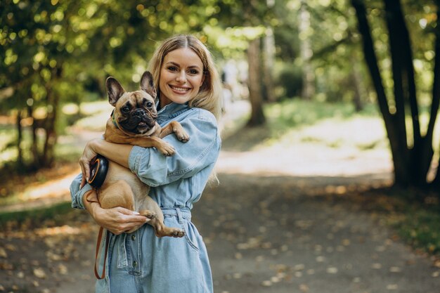 Jeune femme avec son animal de compagnie bouledogue français dans le parc