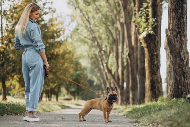 Jeune femme avec son animal de compagnie bouledogue français dans le parc