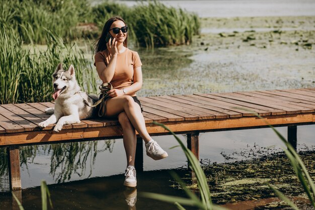 Jeune femme avec son chien husky au bord du lac