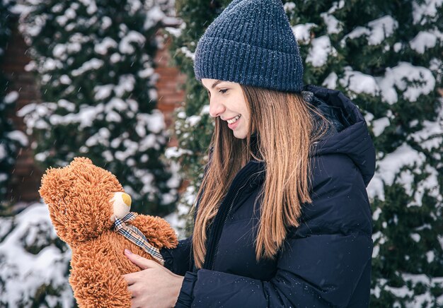 Jeune femme avec son ours en peluche préféré dans ses bras en hiver