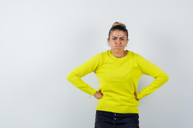 Jeune femme soufflant des joues en pull, jupe en jean et semblant drôle