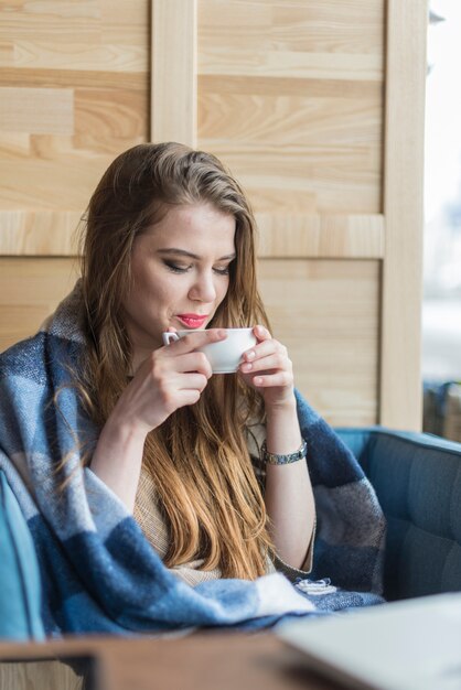 Jeune femme soufflant sa boisson chaude