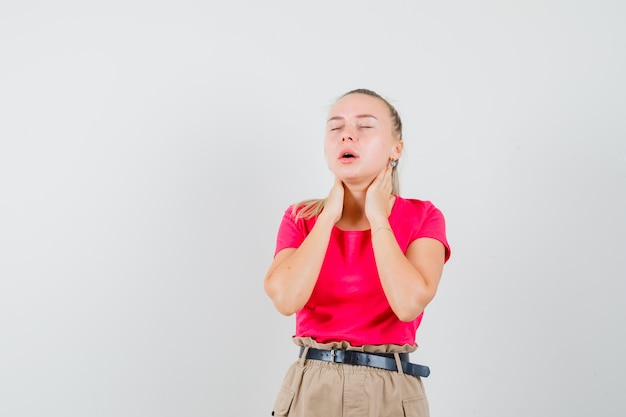 Jeune femme souffrant de douleurs au cou en t-shirt et pantalon et à la fatigue