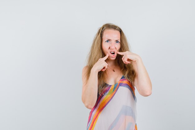 Jeune femme souffrant de maux de dents en robe d'été et à la recherche de mal.