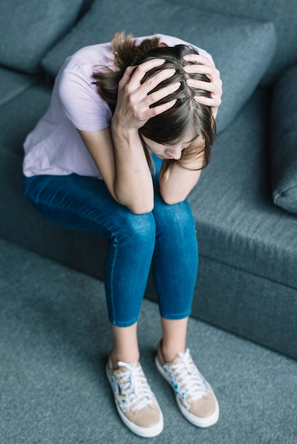 Jeune femme souffrant de maux de tête assis sur un canapé