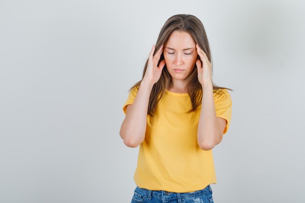 Jeune femme souffrant de maux de tête en t-shirt, short et à la fatigue