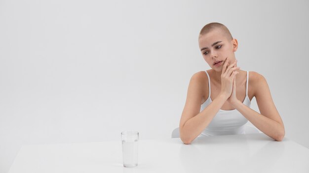 Jeune femme souffrant d'un trouble de l'alimentation en regardant un verre d'eau