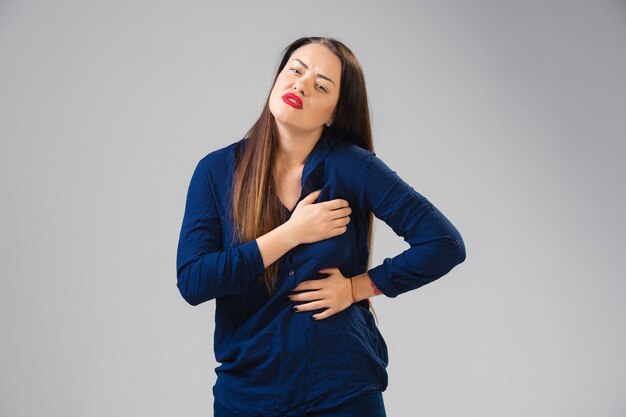 Une jeune femme souffre de douleur, se sent malade et la faiblesse est isolée sur le mur