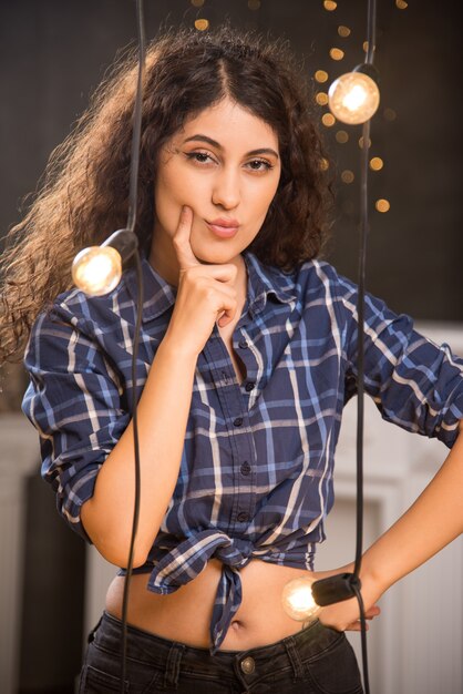 Jeune femme souriante aux cheveux bouclés mettant le doigt sur la joue