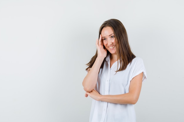 Jeune femme souriante en chemisier blanc et à la recherche d'optimiste.