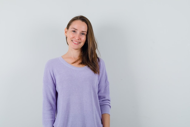 Jeune femme souriante en chemisier lilas et à la mignonne