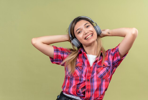 Une jeune femme souriante dans une chemise à carreaux, tenant les mains sur la tête