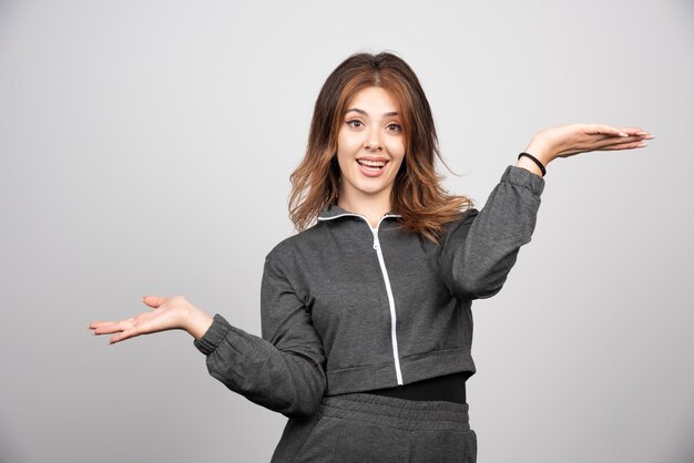 Jeune femme souriante debout et posant avec les mains vers le haut.