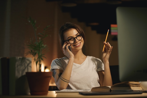 Jeune femme souriante designer parlant par téléphone mobile