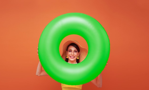 Photo gratuite jeune femme souriante et gaie portant un chapeau tenant un anneau gonflable isolé sur fond orange