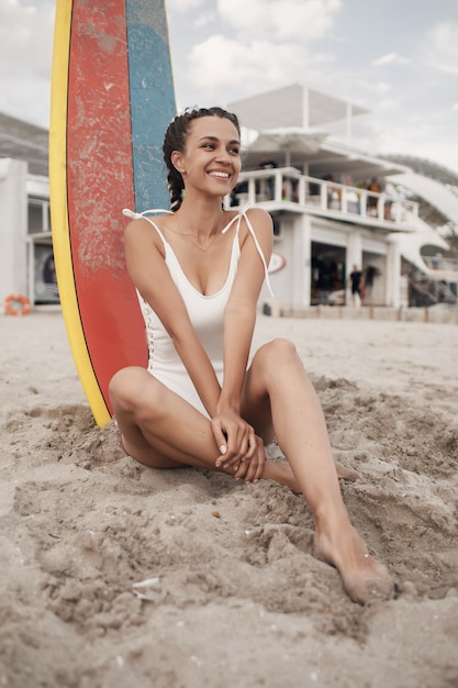 jeune femme souriante avec planche de surf à l'extérieur