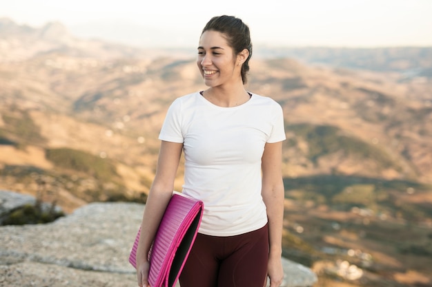 Jeune femme souriante avec tapis de yoga