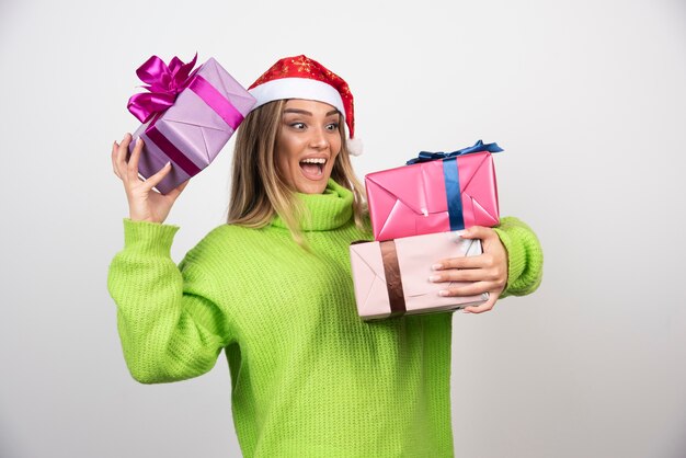 Jeune femme souriante tenant dans les mains des cadeaux de Noël festifs.