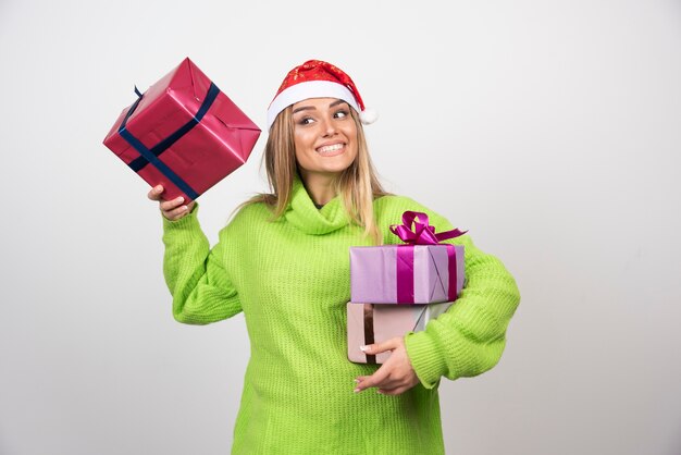 Jeune femme souriante tenant dans les mains des cadeaux de Noël festifs.