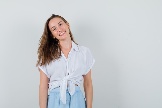 Jeune femme souriante tout en regardant à l'avant en chemisier, jupe et à la recherche positive