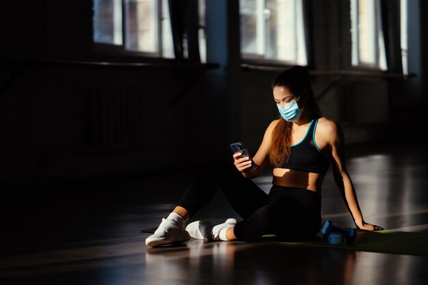 Jeune femme sportive après avoir pratiqué le yoga holding smartphone