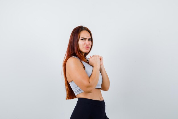 Jeune femme sportive aux cheveux longs dans un haut gris