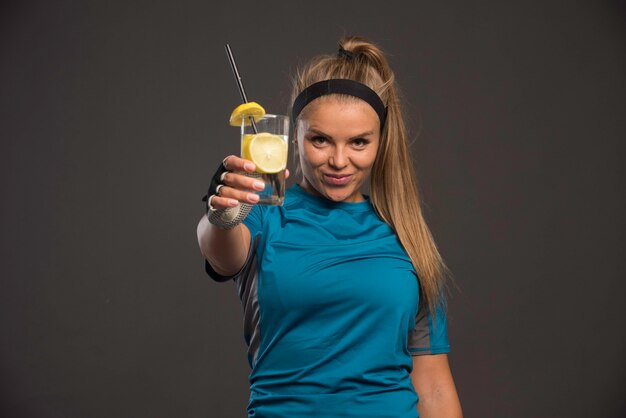 Jeune femme sportive ayant une boisson énergisante au citron après l'entraînement