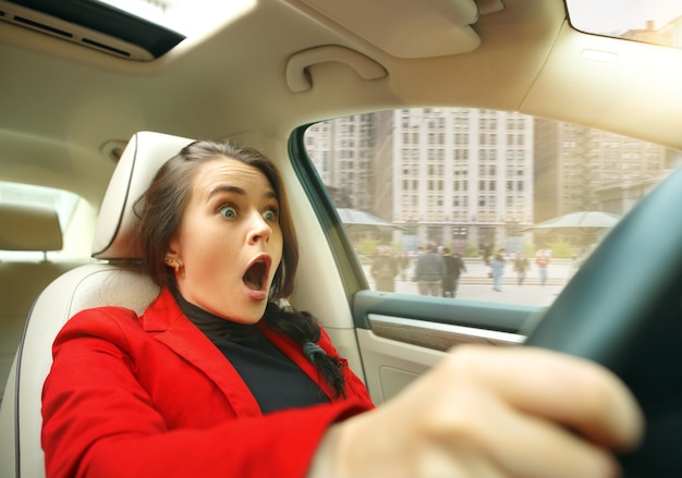 Photo gratuite jeune femme surprise au volant d'une voiture