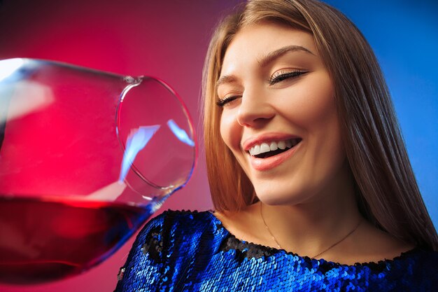 La jeune femme surprise en tenue de fête posant avec un verre de vin.