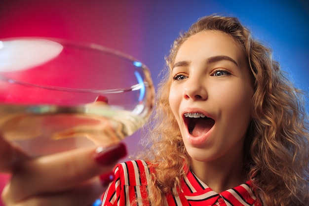 La jeune femme surprise en tenue de fête posant avec un verre de vin.