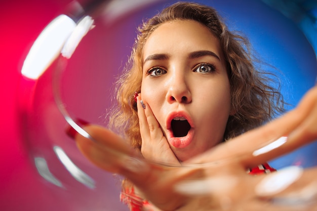 La jeune femme surprise en tenue de fête posant avec un verre de vin.