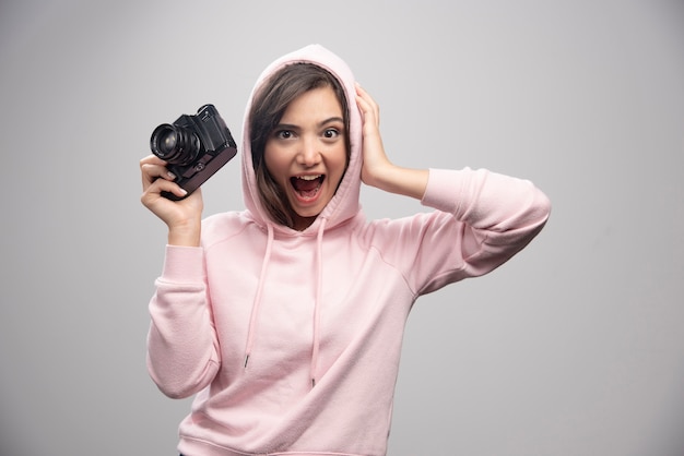 Jeune femme en sweat-shirt tenant la caméra avec bonheur.