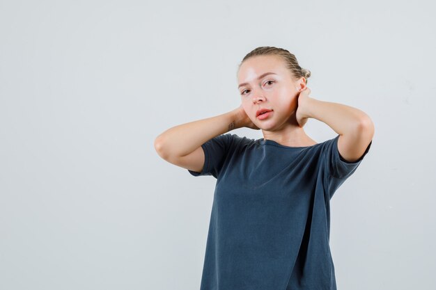 Jeune femme en t-shirt gris touchant le cou avec les mains et à la jolie