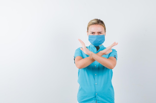 Jeune femme en t-shirt, masque montrant un geste de refus et ayant l'air sérieux