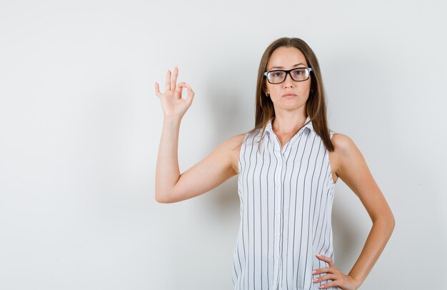 Jeune femme en t-shirt montrant le geste ok et à la vue sérieuse, de face.