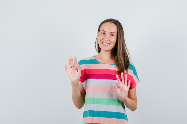 Jeune femme en t-shirt montrant un geste de refus poliment, vue de face.